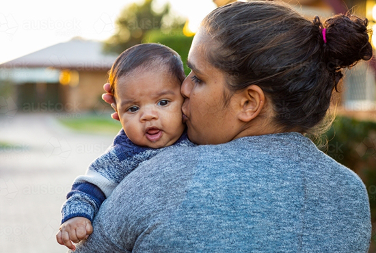 Mother holding child in front of a home